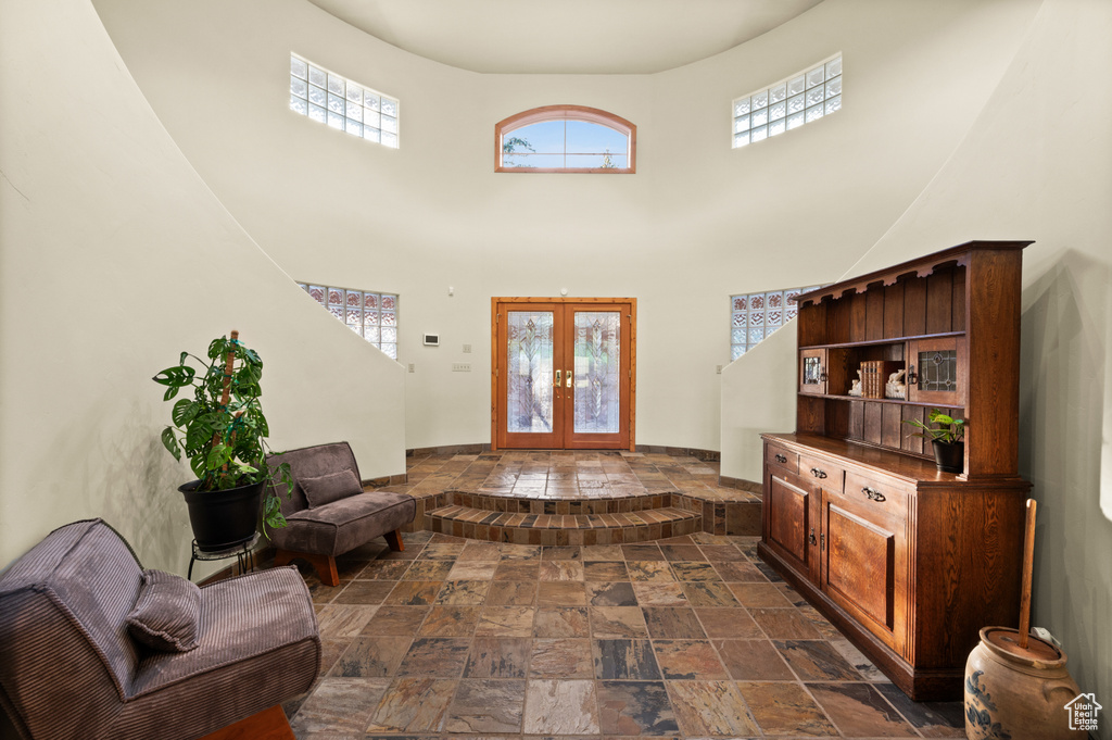 Entryway featuring stone tile floors, french doors, and a towering ceiling