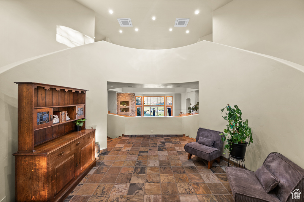 Living area with a high ceiling, stone tile flooring, and recessed lighting