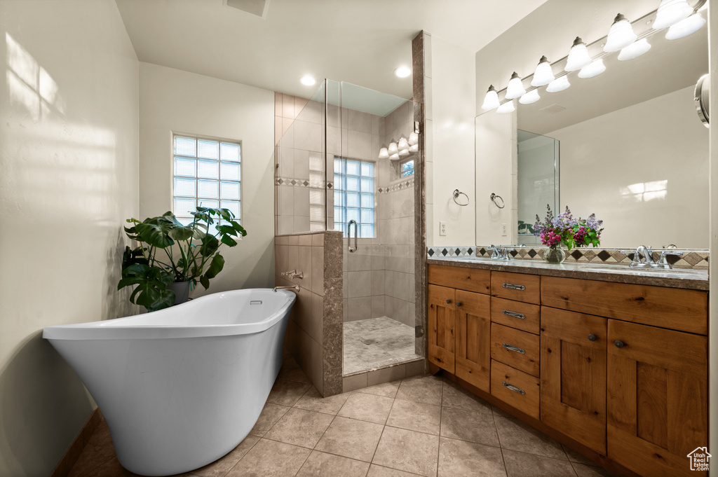 Full bath featuring a stall shower, a freestanding tub, double vanity, and tile patterned flooring
