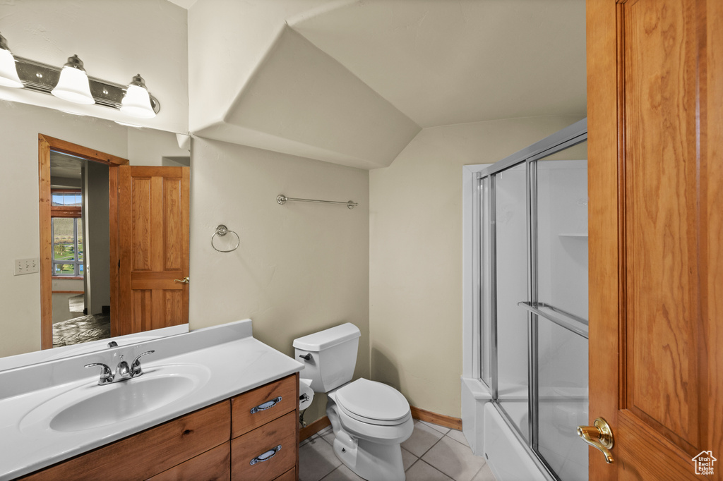 Full bath featuring tile patterned flooring, toilet, vanity, enclosed tub / shower combo, and baseboards