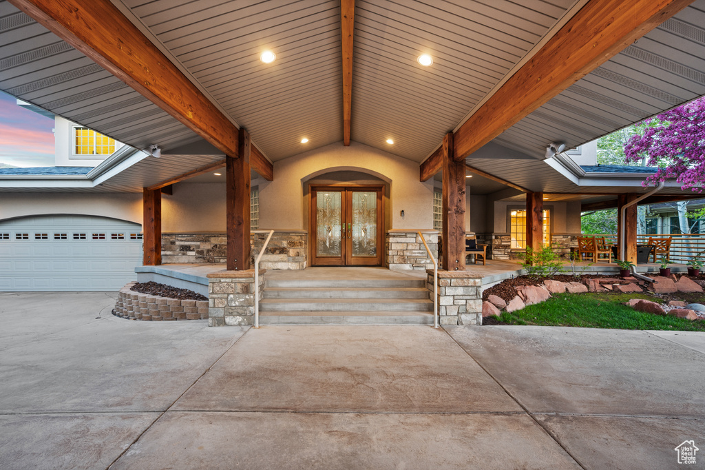 Exterior entry at dusk featuring french doors, stucco siding, and stone siding