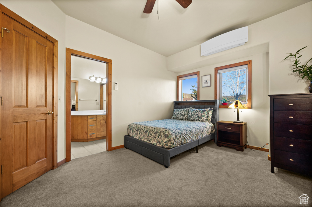Bedroom with an AC wall unit, light colored carpet, baseboards, connected bathroom, and a ceiling fan