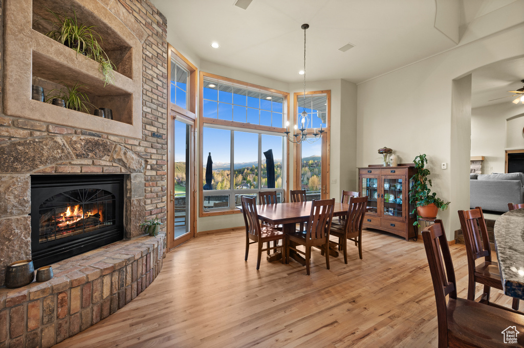Dining space with a fireplace, light wood-style flooring, a chandelier, recessed lighting, and a mountain view