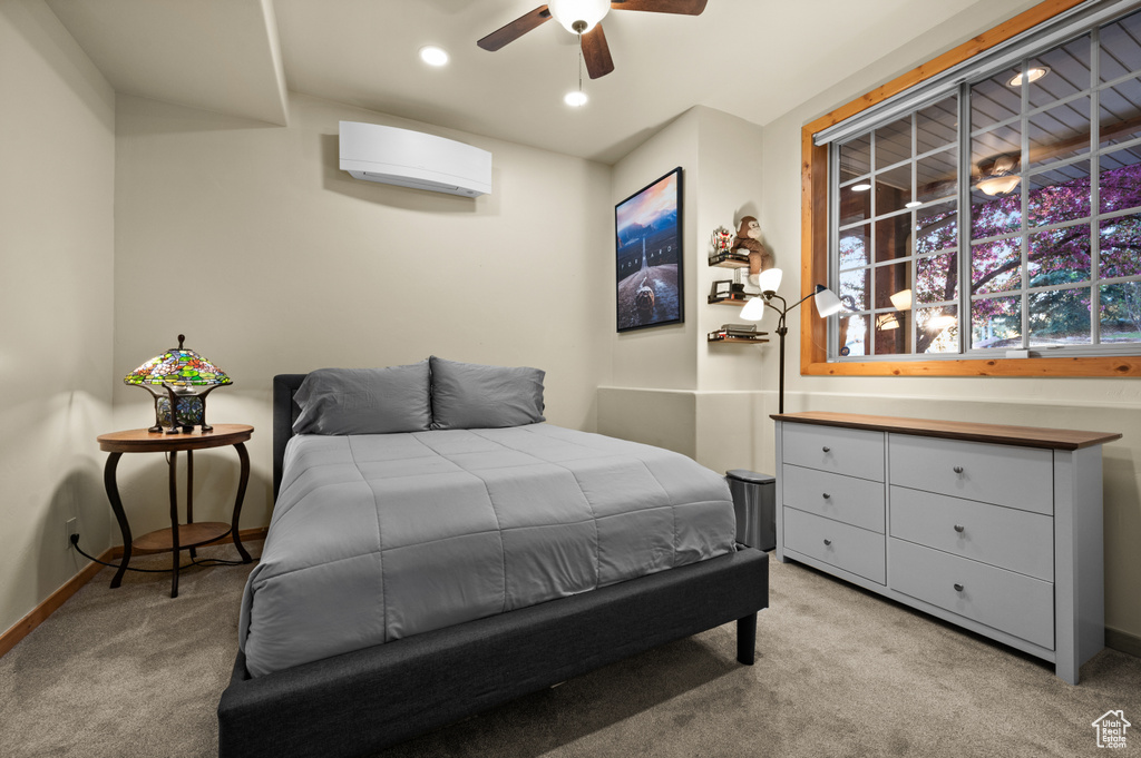 Bedroom with light colored carpet, baseboards, a wall mounted air conditioner, recessed lighting, and ceiling fan