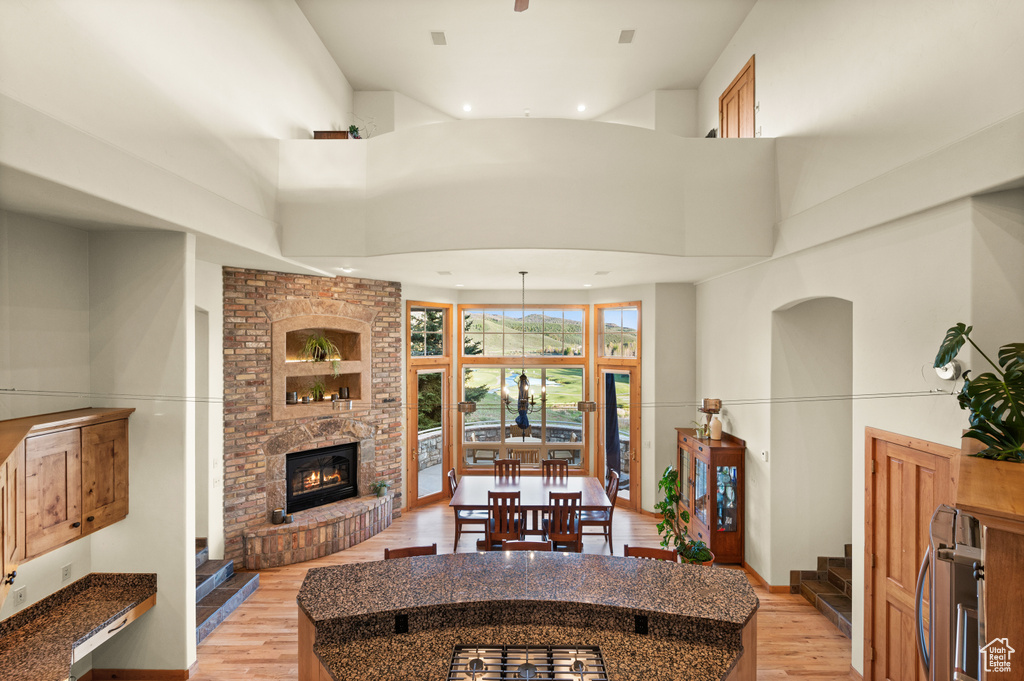 Kitchen featuring a towering ceiling, light wood-style flooring, recessed lighting, beverage cooler, and a fireplace