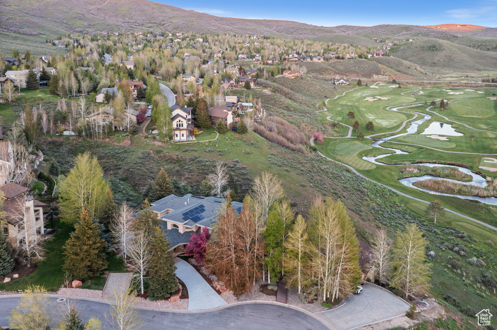 Aerial overview of property's location featuring a golf course, nearby suburban area, and a mountainous background