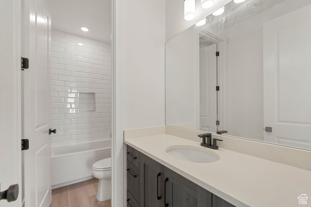 Full bath featuring toilet, vanity, wood finished floors, and bathtub / shower combination