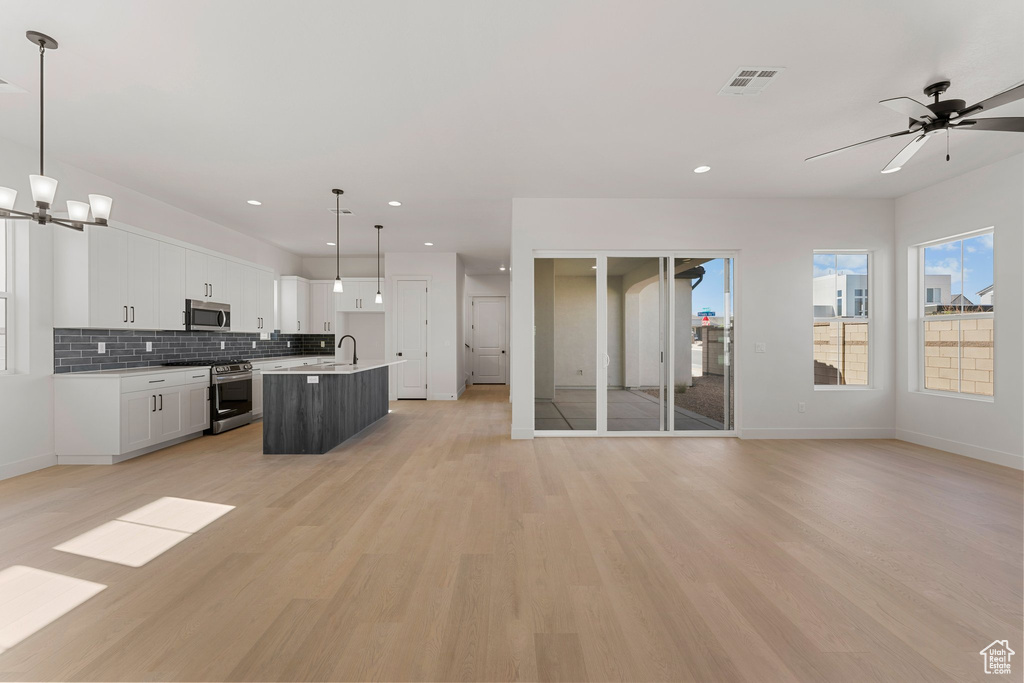 Kitchen featuring appliances with stainless steel finishes, open floor plan, a sink, baseboards, and recessed lighting