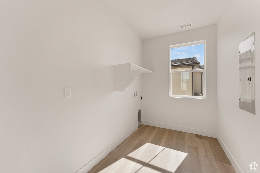 Laundry room with baseboards, light wood-style floors, washer hookup, electric panel, and electric dryer hookup