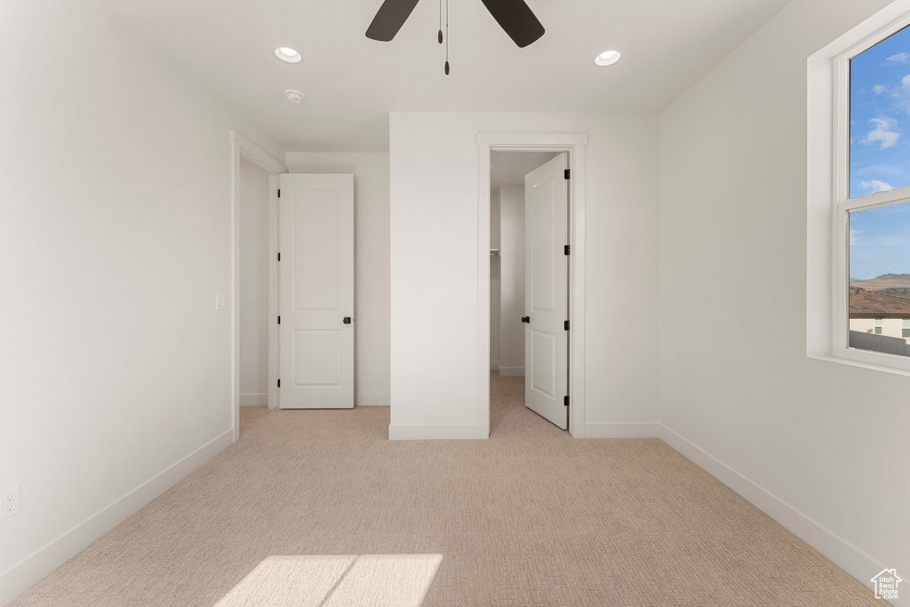 Unfurnished bedroom with light carpet, baseboards, recessed lighting, a ceiling fan, and a spacious closet
