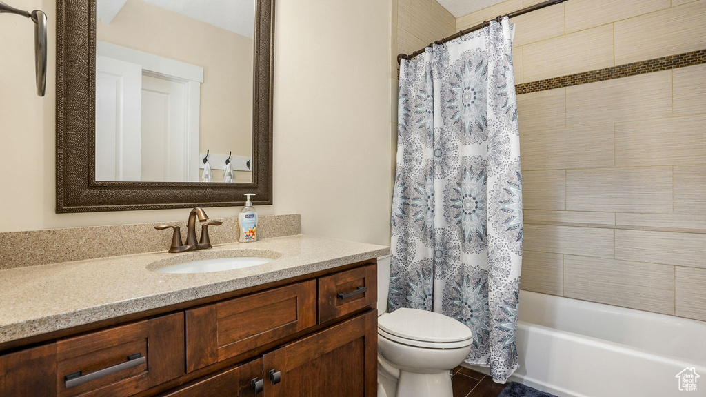 Bathroom featuring toilet, vanity, shower / bath combo with shower curtain, and tile patterned flooring