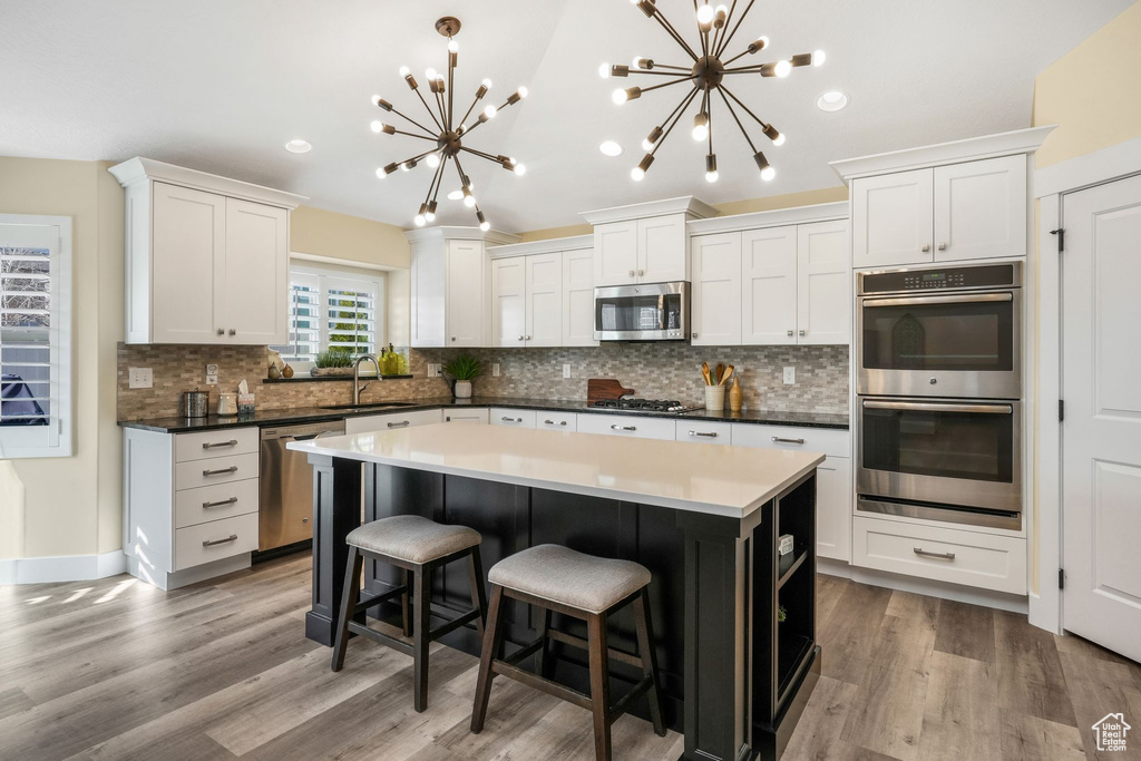 Kitchen featuring appliances with stainless steel finishes, a chandelier, a sink, backsplash, and recessed lighting