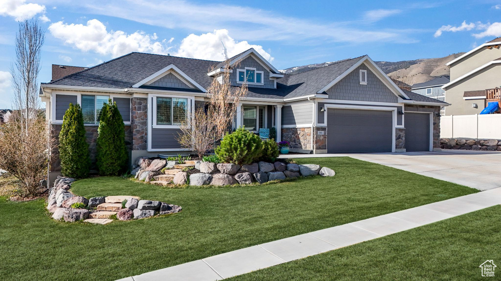 Craftsman house with stone siding, an attached garage, concrete driveway, and a shingled roof