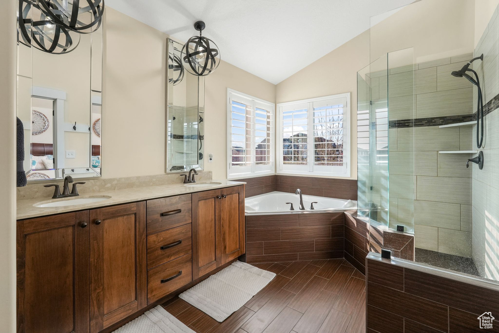 Ensuite bathroom with lofted ceiling, a garden tub, tiled shower, and double vanity