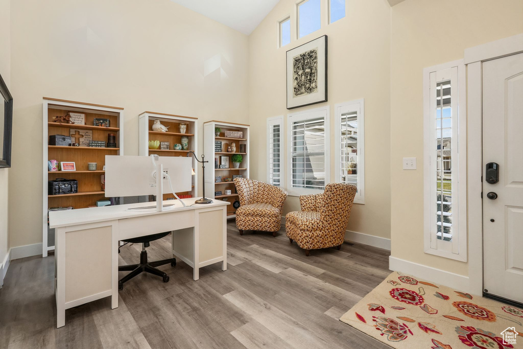 Office space with high vaulted ceiling, light wood finished floors, and baseboards