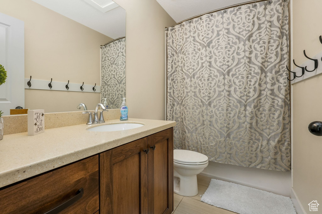 Full bath featuring toilet, vanity, and tile patterned flooring
