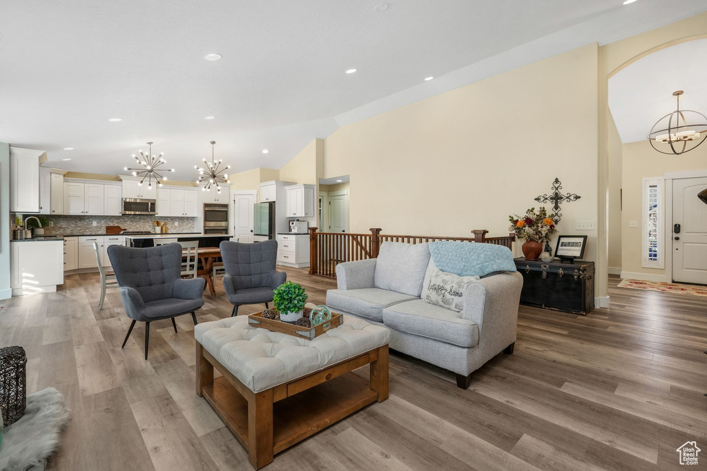 Living area featuring a chandelier, lofted ceiling, light wood-style floors, and recessed lighting