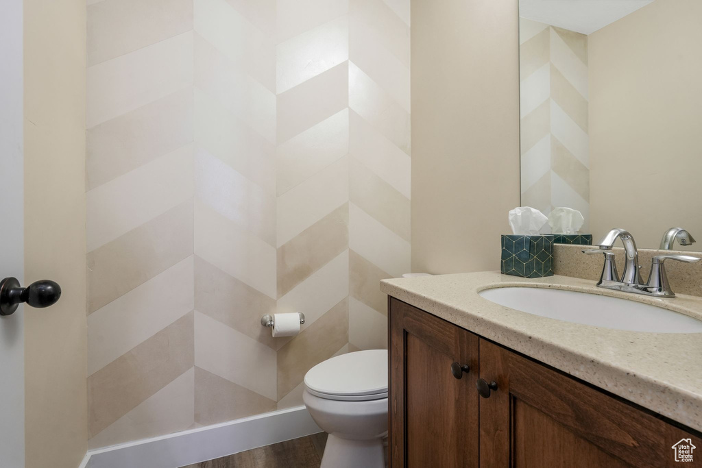 Bathroom with toilet, vanity, and wood finished floors