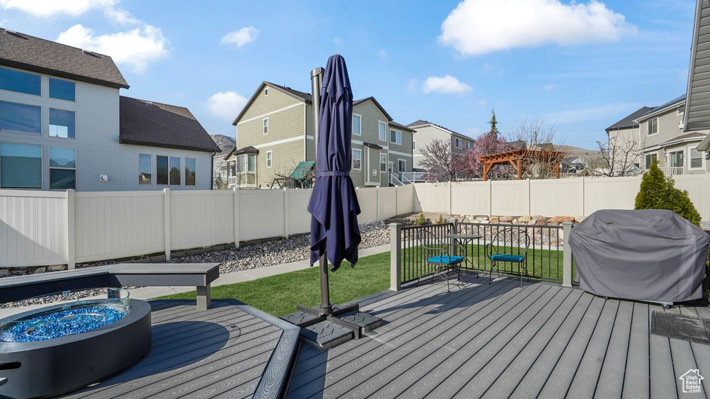 Wooden terrace featuring a residential view, a grill, and a fire pit