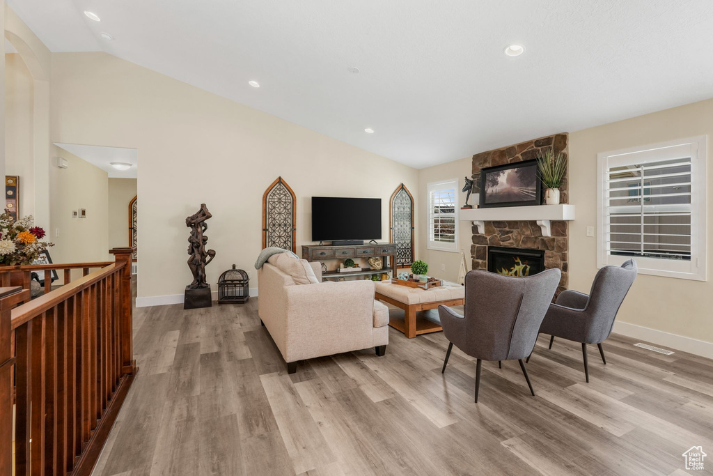Living area featuring vaulted ceiling, light wood-type flooring, a fireplace, baseboards, and recessed lighting