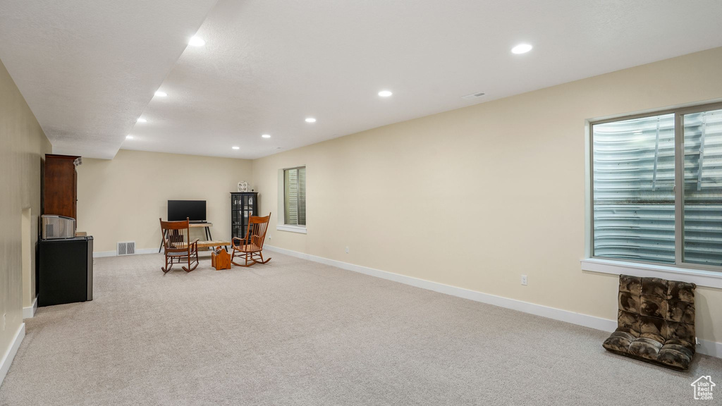 Living area with light colored carpet, recessed lighting, and baseboards