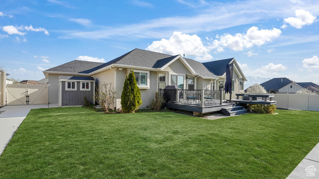 Back of house with a gate, a deck, stucco siding, and a shingled roof