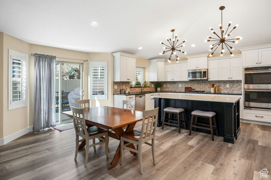 Dining room featuring a chandelier, light wood-style floors, recessed lighting, vaulted ceiling, and baseboards