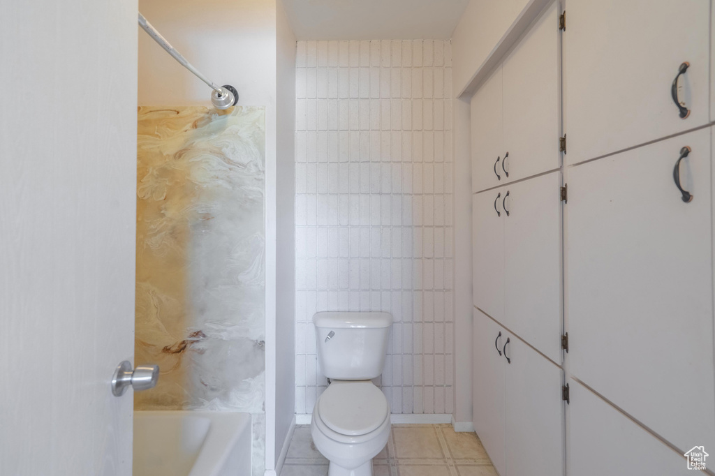 Bathroom with toilet, tile walls, and tile patterned flooring