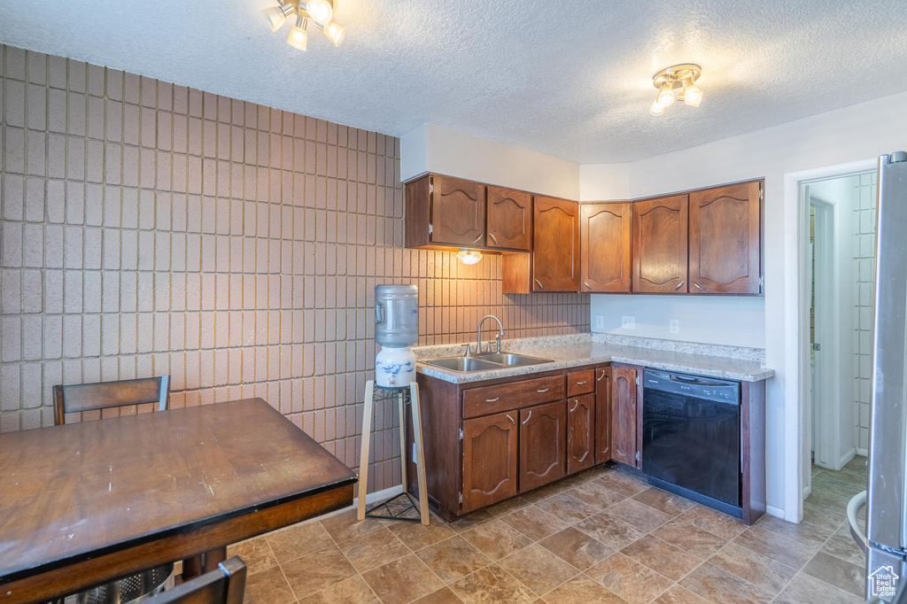 Kitchen featuring black dishwasher, a sink, light countertops, a textured ceiling, and decorative backsplash