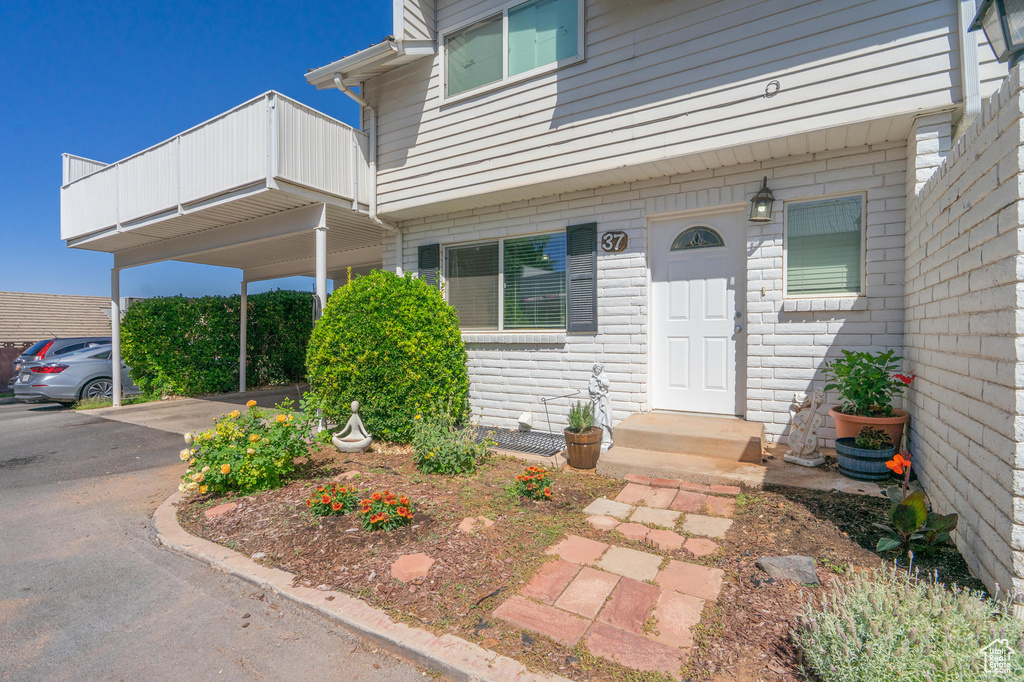 View of exterior entry featuring driveway and a balcony