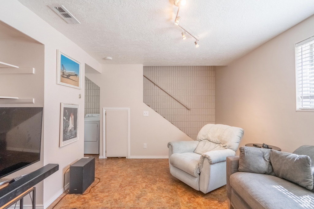 Sitting room with washer / clothes dryer, carpet, a textured ceiling, track lighting, and baseboards
