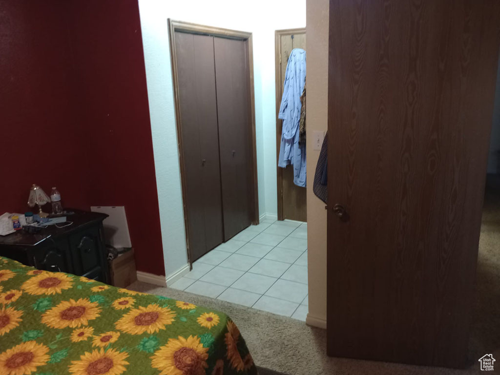 Bedroom with light colored carpet, light tile patterned floors, and baseboards
