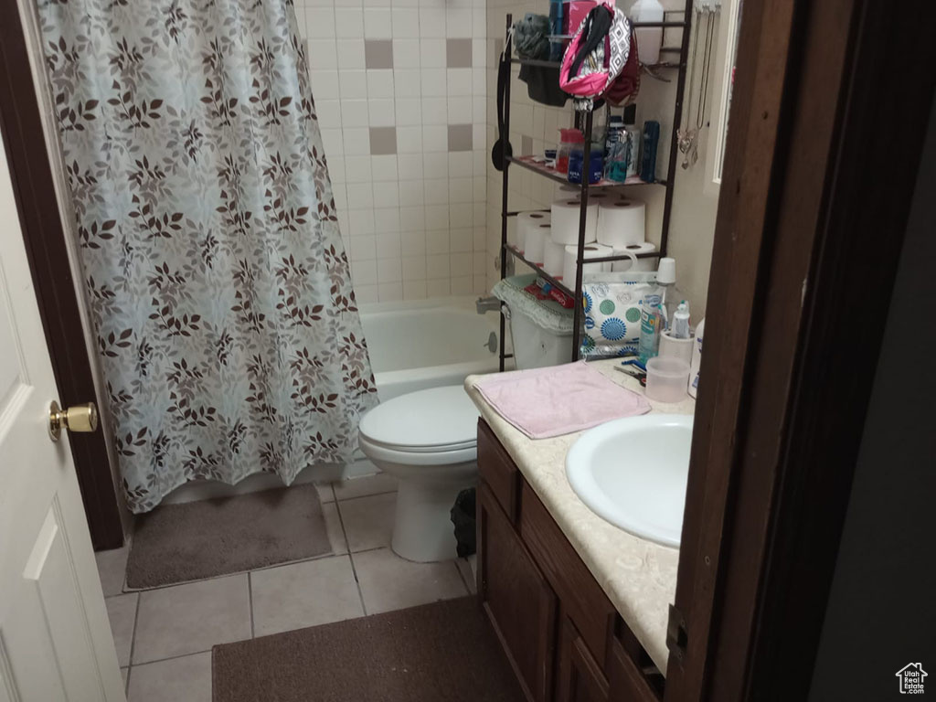Full bath featuring tile patterned floors, shower / bath combo with shower curtain, toilet, and vanity