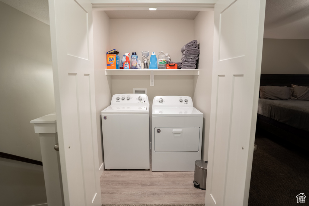 Laundry area with washer and dryer and light wood finished floors
