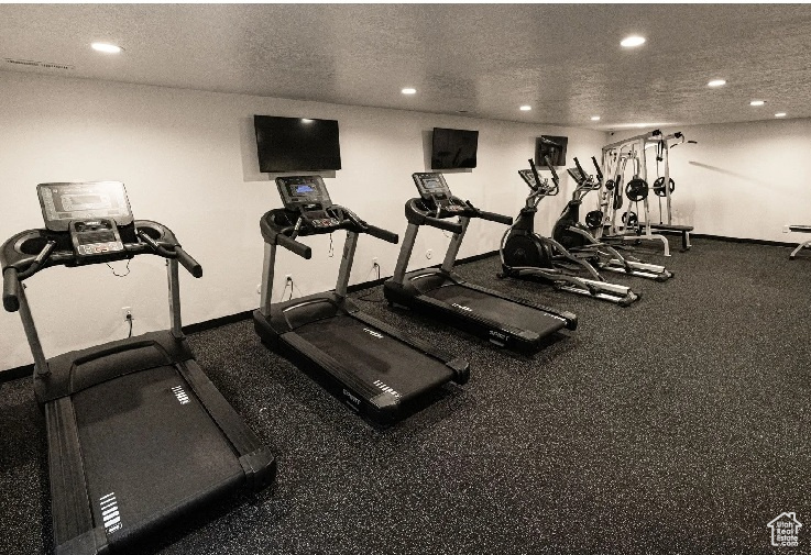 Workout area featuring recessed lighting, a textured ceiling, and baseboards