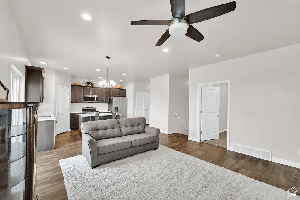 Living area featuring ceiling fan, dark wood-type flooring, baseboards, recessed lighting, and a chandelier