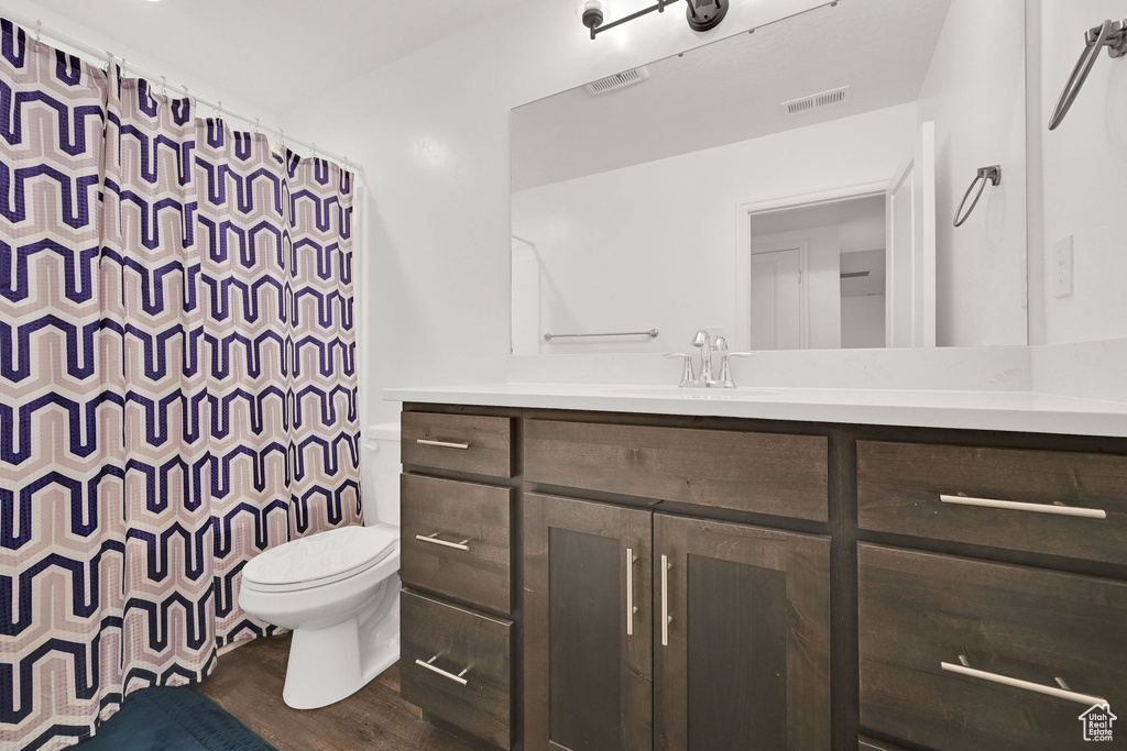 Full bathroom featuring toilet, vanity, wood finished floors, and a shower with shower curtain