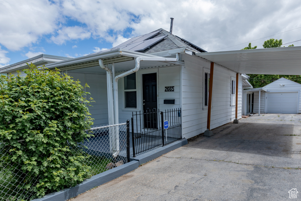 View of front of house with asphalt driveway, an outdoor structure, and a garage