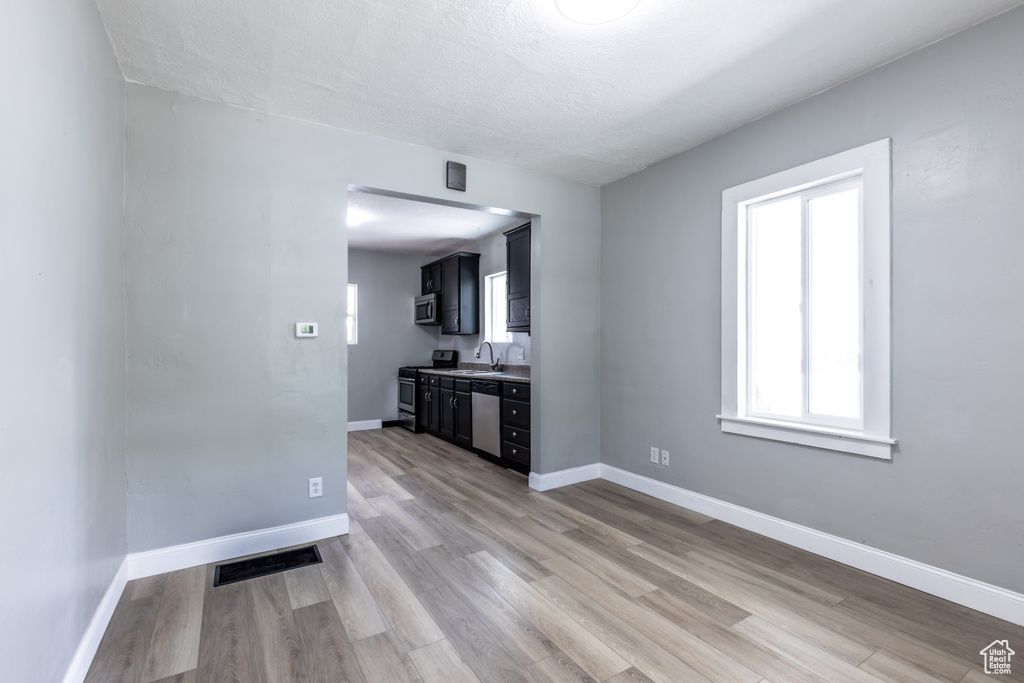 Unfurnished living room with light wood-type flooring, baseboards, and a sink
