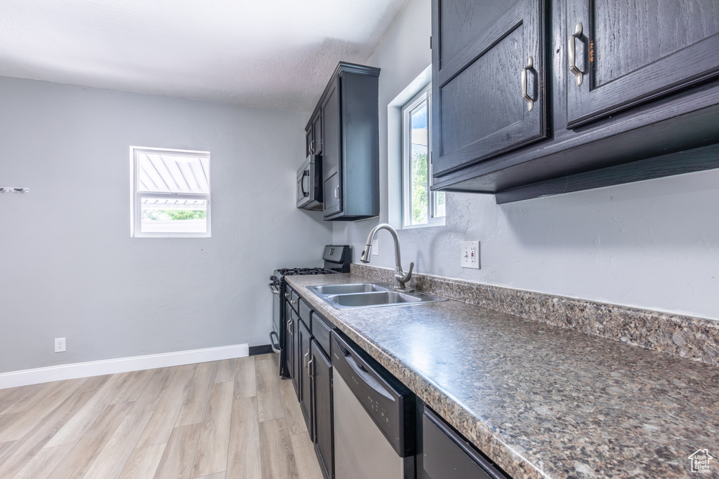 Kitchen with stainless steel appliances, a sink, healthy amount of natural light, and light wood-style floors