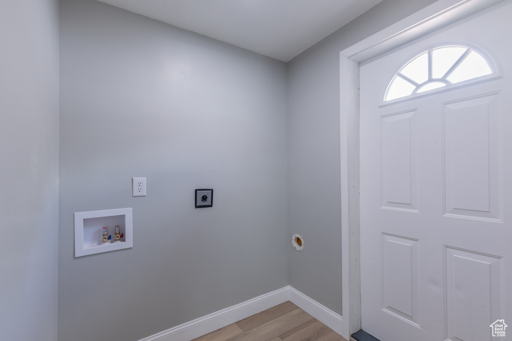 Laundry room featuring hookup for an electric dryer, hookup for a washing machine, light wood-style floors, and baseboards