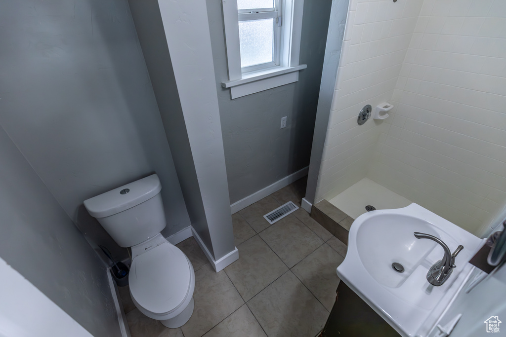 Bathroom with baseboards, a shower stall, toilet, tile patterned floors, and a sink