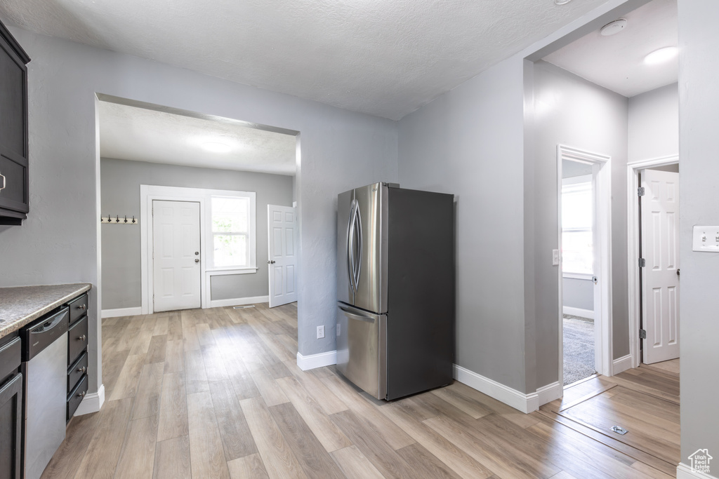 Kitchen with appliances with stainless steel finishes, light wood finished floors, light countertops, and baseboards