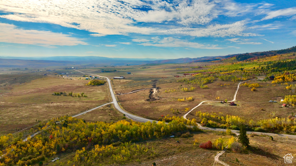 Aerial view of property and surrounding area featuring a mountain backdrop and rural landscape