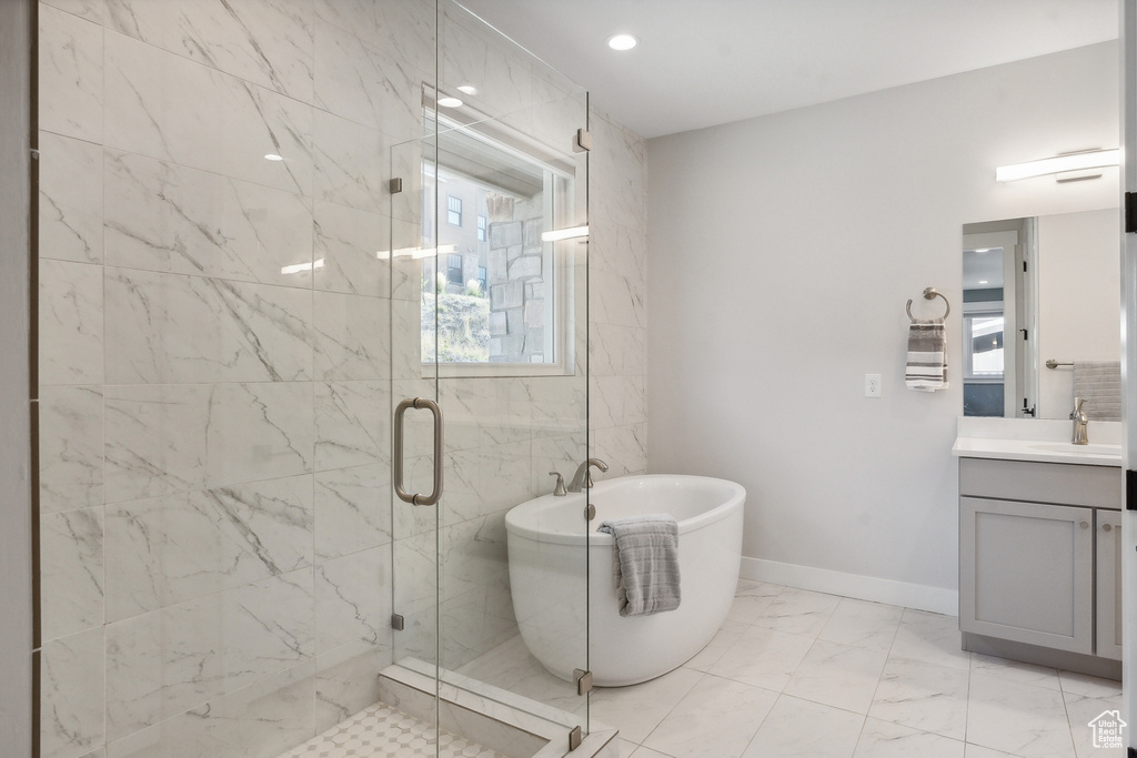 Bathroom featuring a stall shower, a freestanding bath, marble finish floors, vanity, and baseboards