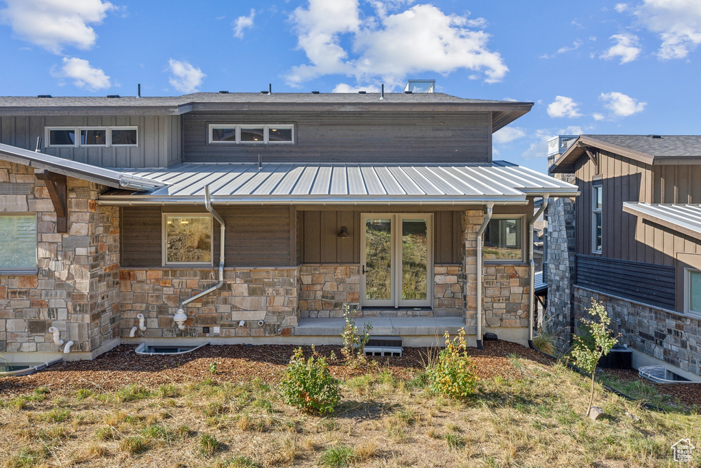 View of front of home with stone siding, covered porch, board and batten siding, metal roof, and a standing seam roof