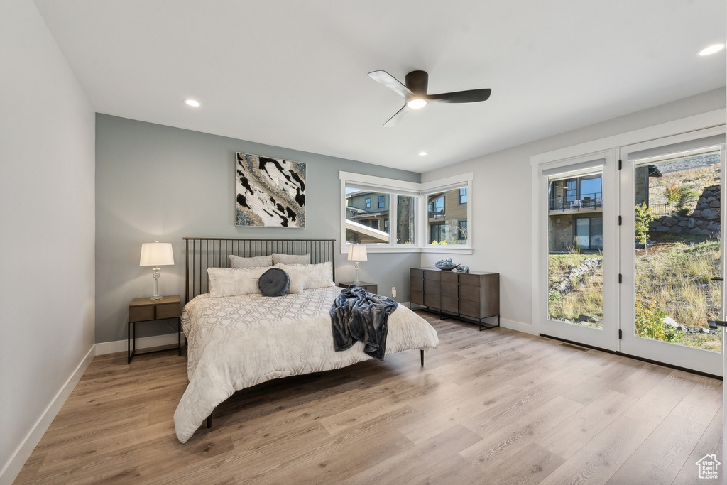 Bedroom with access to exterior, wood finished floors, multiple windows, and recessed lighting