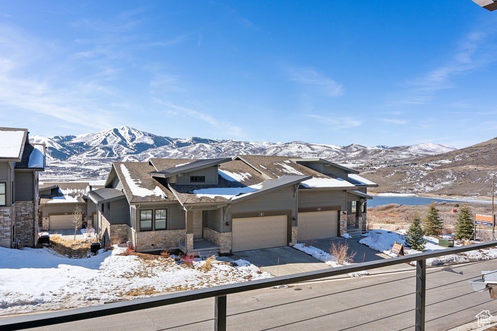 View of front facade with a garage, driveway, a mountain view, and stone siding