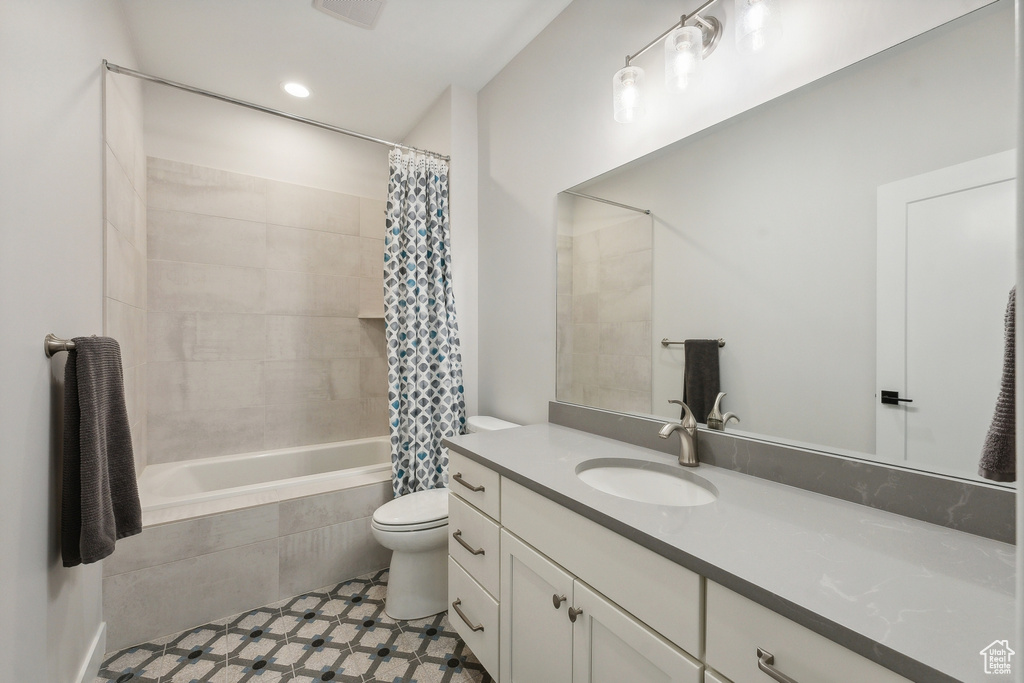 Full bathroom featuring toilet, vanity, tiled shower / bath combo, and tile patterned flooring