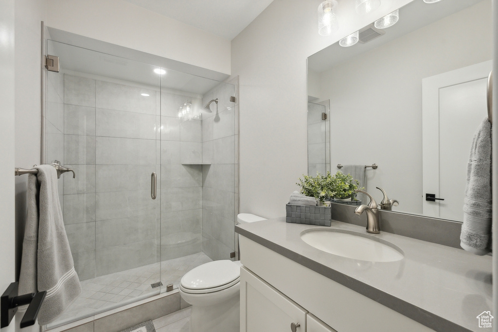 Full bathroom with toilet, vanity, a stall shower, and tile patterned flooring